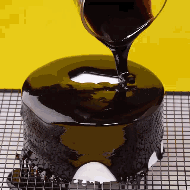 a cake with a hole in the middle is being covered with chocolate icing