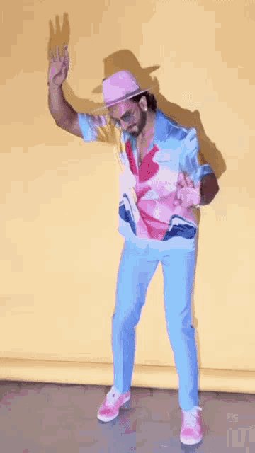 a man in a pink hat and a colorful shirt is dancing .