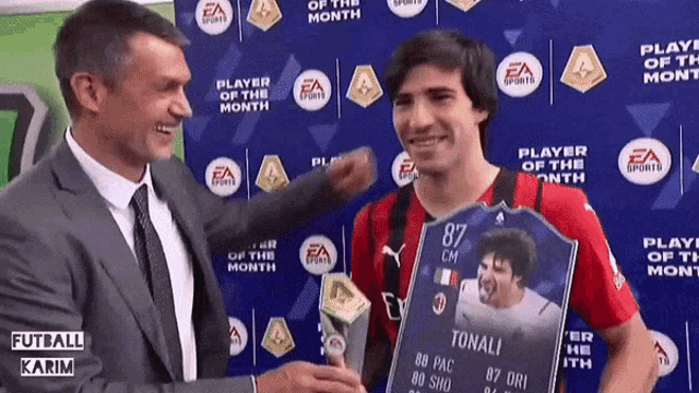a man in a suit and tie holds a card that says tonali on it