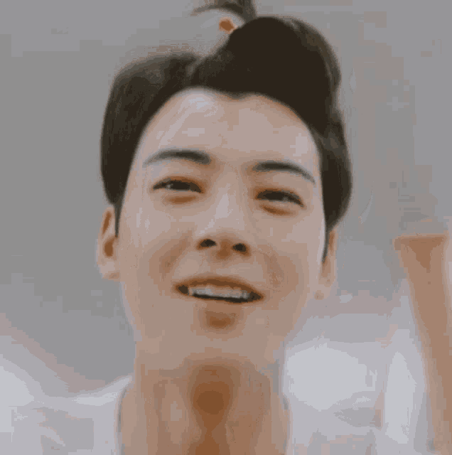a close up of a man 's face with a bun in his hair smiling