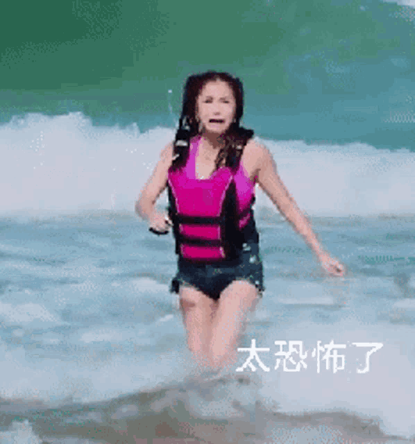 a woman wearing a life vest is running out of the ocean