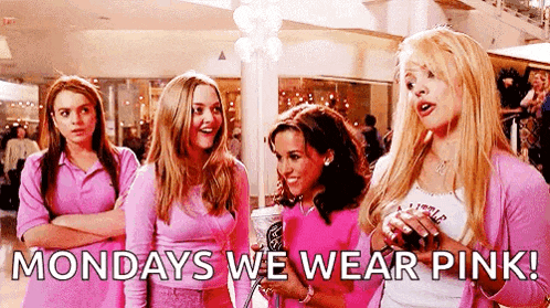 a group of girls are standing next to each other in a shopping mall wearing pink .