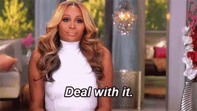 a woman in a white dress is sitting in front of a window and saying `` deal with it '' .