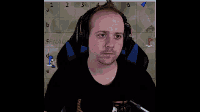 a man wearing headphones sits in front of a chess board with the letter a on it