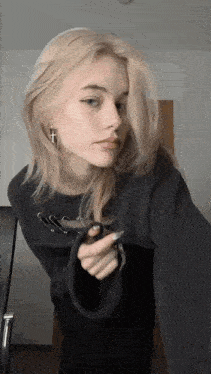 a woman with blonde hair is wearing a black sweater and earrings with a cross on them .