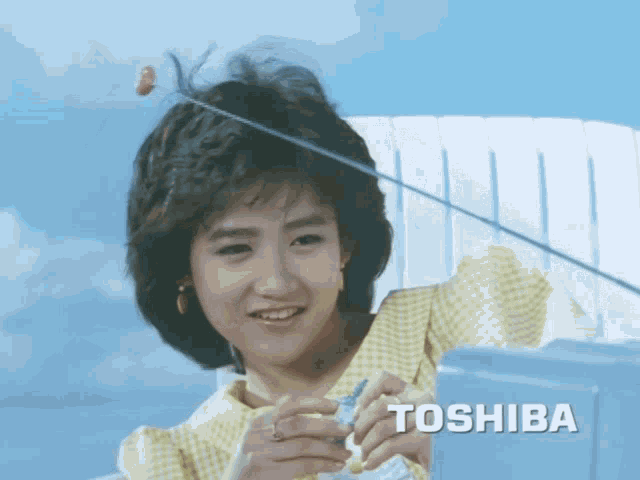 a woman in a yellow plaid shirt is holding a toshiba device