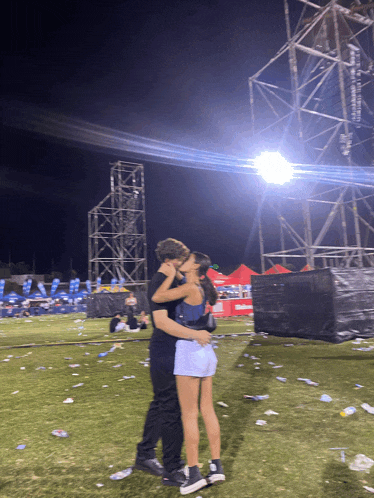 a man and a woman are kissing in a field with a banner that says budweiser on it