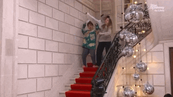 two children standing on a set of stairs with a disney logo on the bottom right