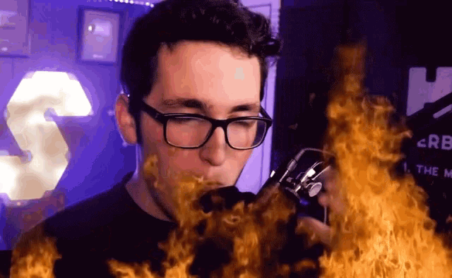 a man wearing glasses is smoking a cigarette with flames around his face