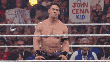 a man in a wrestling ring has a sign that says john cena kid