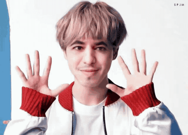 a young man wearing a white shirt and a red sweater is giving a peace sign