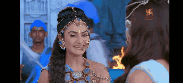 a woman in a blue dress is smiling at another woman in a blue dress .