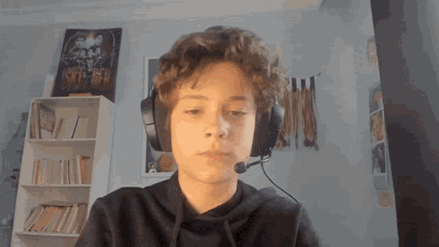 a boy wearing headphones and a microphone in front of a bookshelf