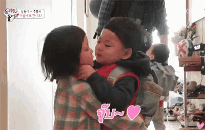 a little girl is kissing a little boy on the cheek while holding him .