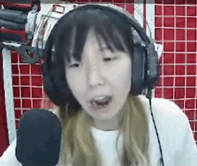 a young woman wearing headphones and a microphone is talking into a microphone .