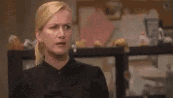 a woman in a black dress is making a funny face in a room .