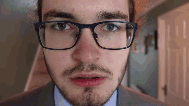 a close up of a man 's face with glasses and a beard