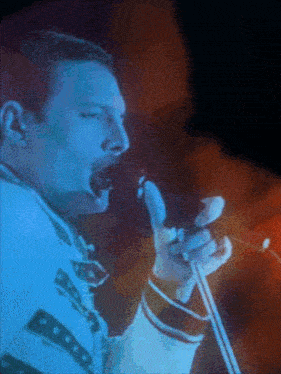 a close up of a man singing into a microphone with a blue background