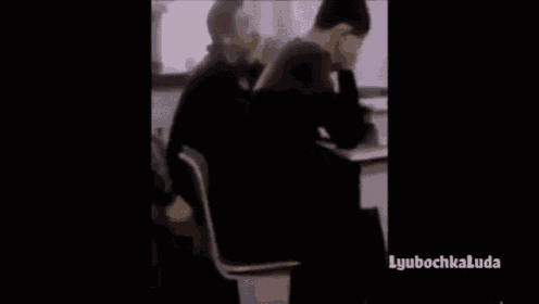 a man is sitting at a desk with his head in his hands and covering his face .