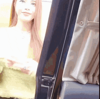 a woman in a green sweater is standing next to a black door .