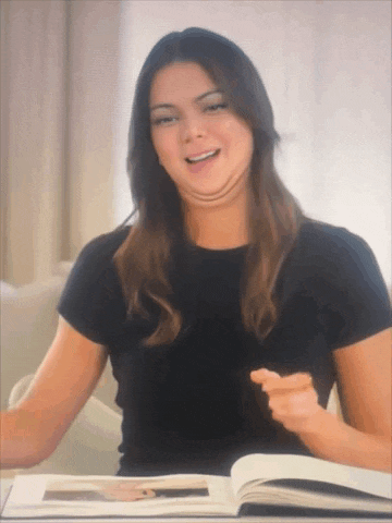 a woman in a black shirt is sitting at a table with a book