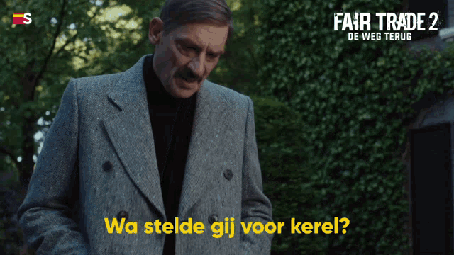 a man with a mustache is standing in front of a fair trade 2 sign