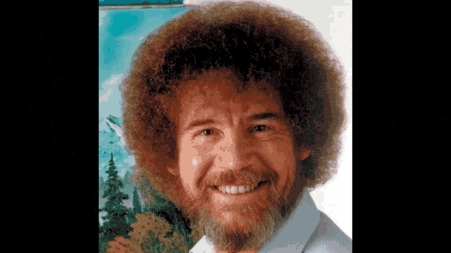 a man with a beard and curly hair is smiling in front of a painting