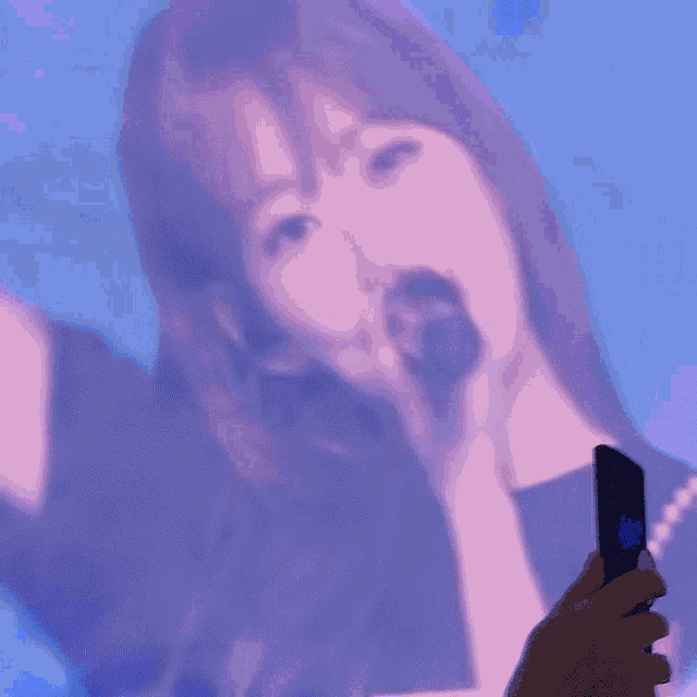 a close up of a woman singing into a microphone while making a peace sign .