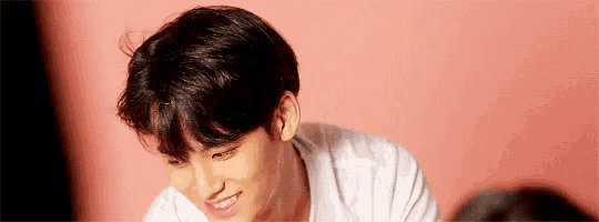 a young man in a white shirt is smiling and looking down .