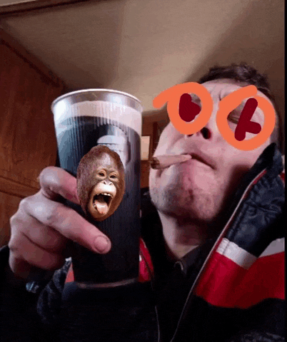a man smoking a cigarette while holding a glass with a monkey face on it