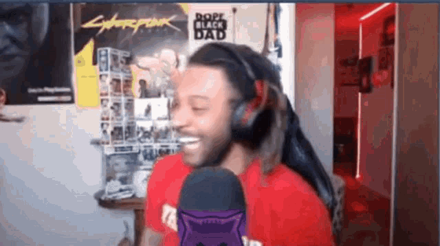 a man wearing headphones is smiling in front of a cyberpunk poster .
