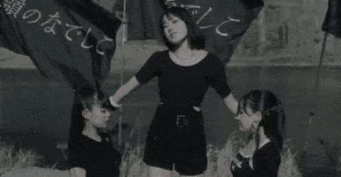 a black and white photo of three girls with one wearing a shirt that says real