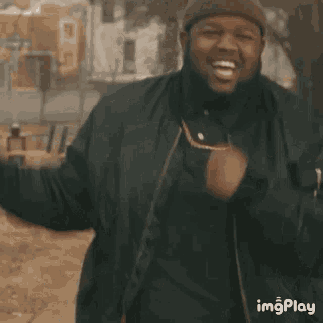 a man wearing a black jacket and a beanie is smiling and dancing in a park .