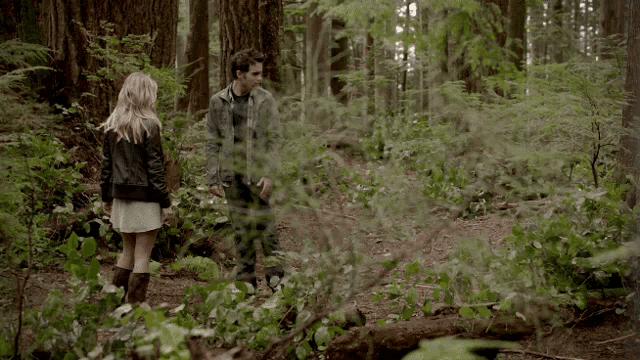 a man and a woman standing in a forest