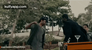two men are standing next to each other in a park and one of them is sweating .