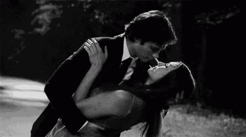 a man in a suit and tie is kissing a woman in a dress .