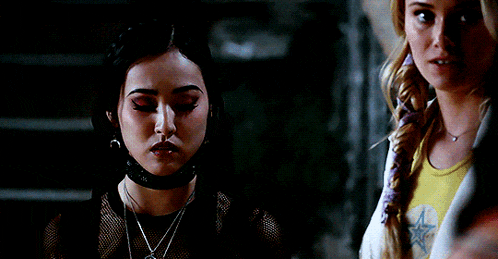 a woman wearing a choker and earrings looks at another woman