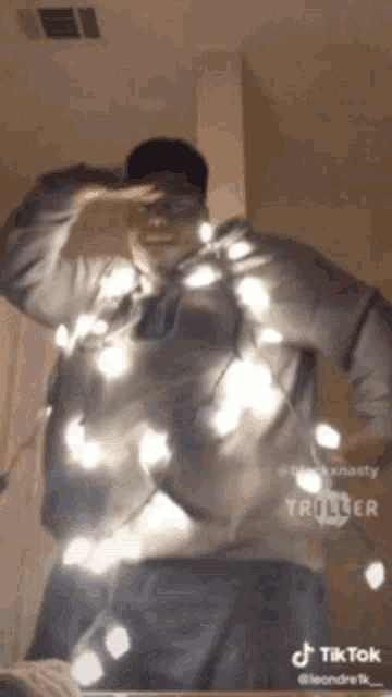 a man is standing in front of a mirror with christmas lights on his sweater