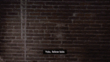 a man with a beard is holding a scooter and says " yolo fellow kids " at the bottom