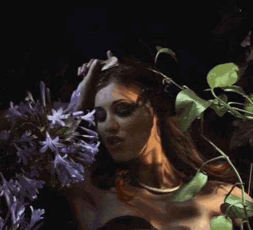 a woman in a black dress holds purple flowers in her hands