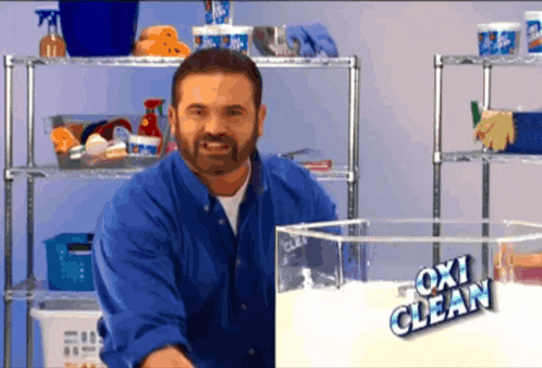a man in a blue shirt is standing next to a box of oxi clean