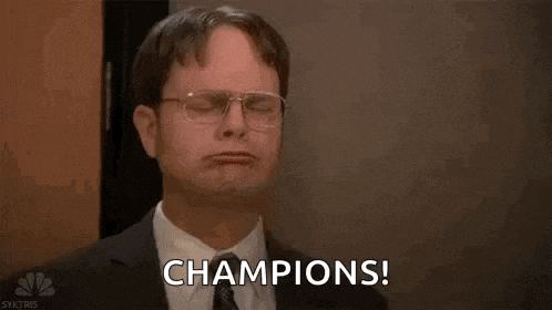 a man in a suit and tie is holding his arms up in the air and saying `` champions ! ''