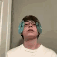 a young man wearing glasses and a pair of ear plugs on his ears .