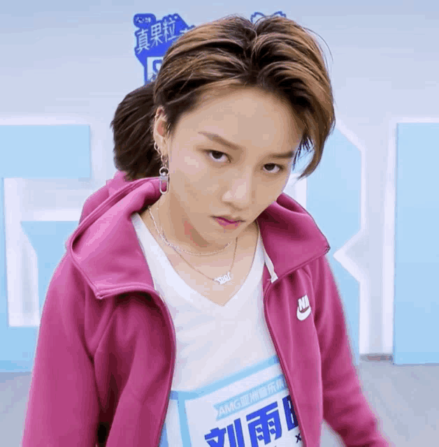 a girl wearing a pink nike jacket and a white shirt with chinese writing on it