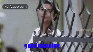 a woman is standing behind a fence and says good morning .