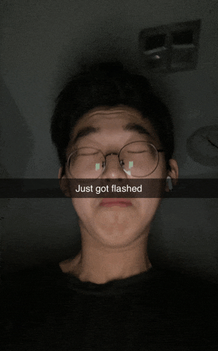a young man wearing glasses has just got flashed written on the bottom of his face