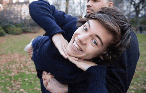 a man is carrying another man on his back and they are smiling for the camera