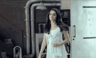 a woman in a white dress is walking through a doorway in a room .