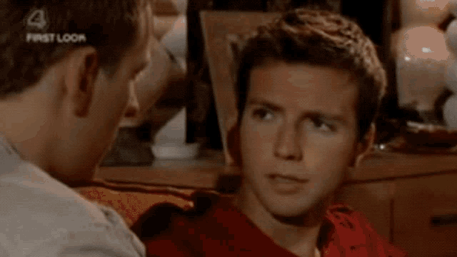 two men are looking at each other and one of them is wearing a red shirt