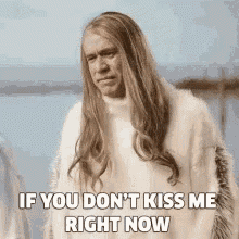 a man with long hair is wearing a white sweater and a fur coat .